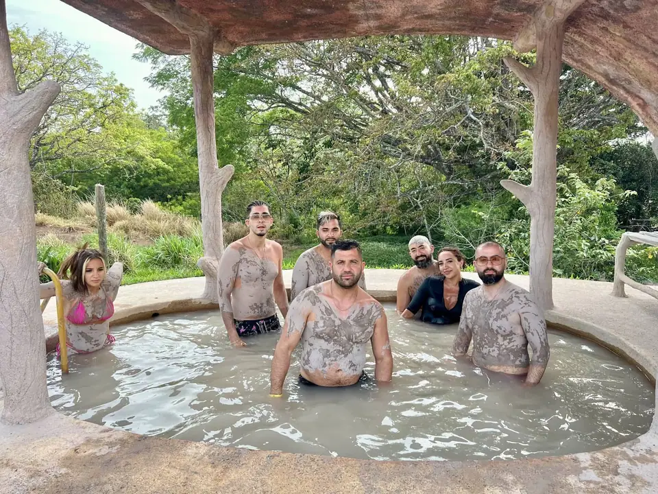 Visitors in a mud pool under a wooden hut at Las Hornillas